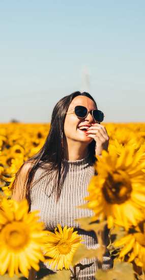 Young woman in a field of sunflowers wearing sunglasses
